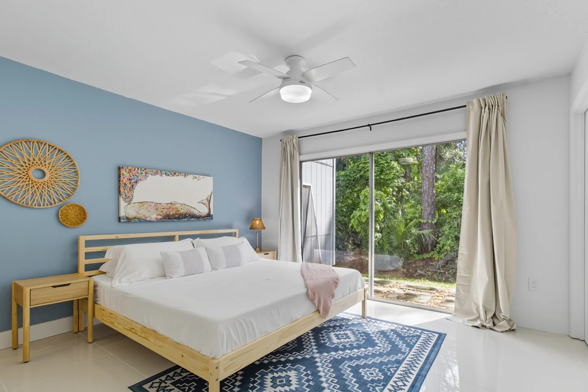 Primary bedroom with blue accent wall and garden view at We Are Blissful